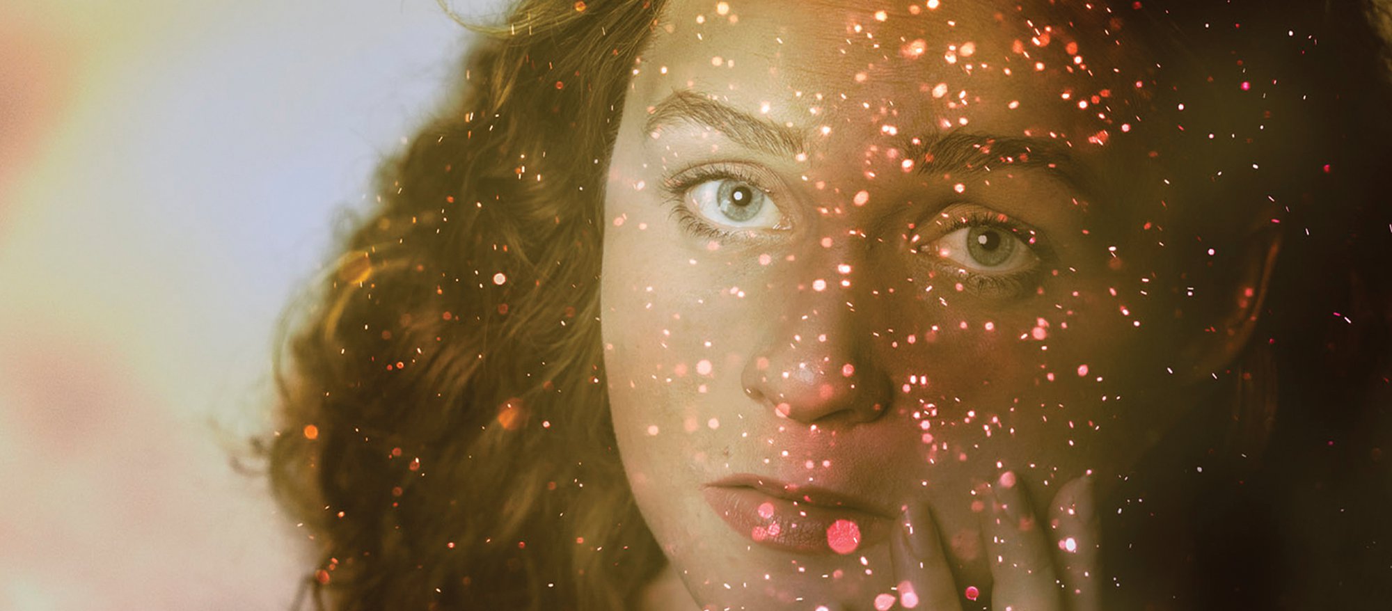 An image of a woman's face with sparkles overlaid